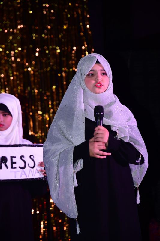 A student speaking on stage with a microphone